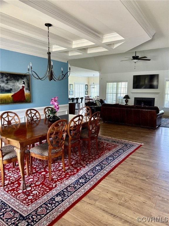 dining area featuring a fireplace, ceiling fan with notable chandelier, wood finished floors, beamed ceiling, and coffered ceiling