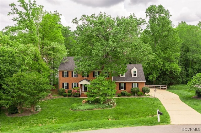 colonial-style house featuring brick siding, a front yard, and concrete driveway