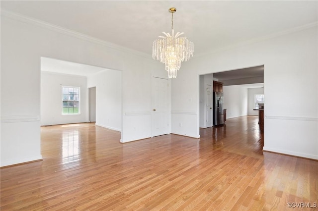 unfurnished dining area with crown molding, baseboards, light wood-style flooring, and a notable chandelier