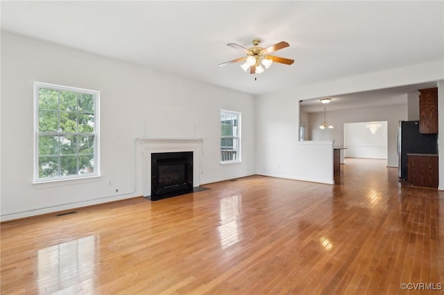 unfurnished living room featuring a healthy amount of sunlight, ceiling fan, wood finished floors, and visible vents