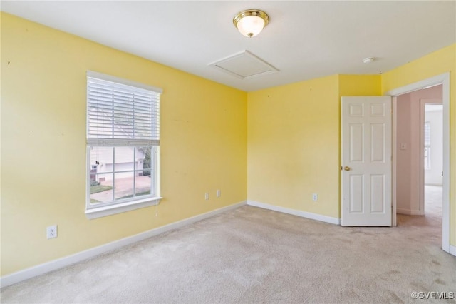 spare room with baseboards, attic access, and carpet flooring