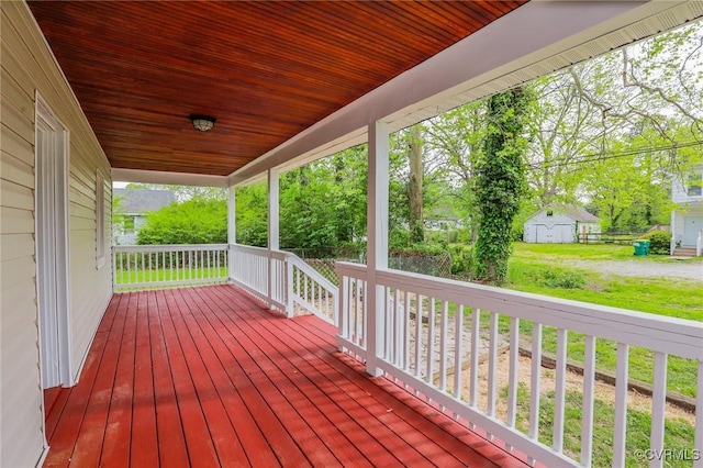 wooden deck with a storage shed and covered porch