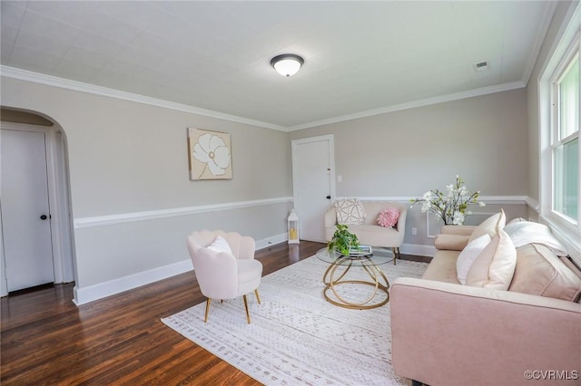 living area with wood finished floors, arched walkways, and crown molding