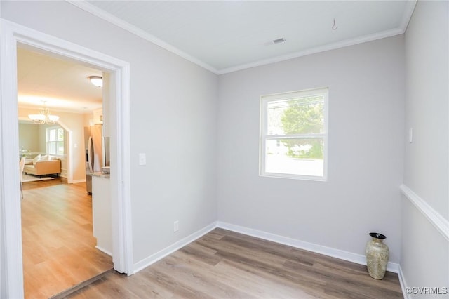 empty room featuring light wood-type flooring, visible vents, an inviting chandelier, and crown molding