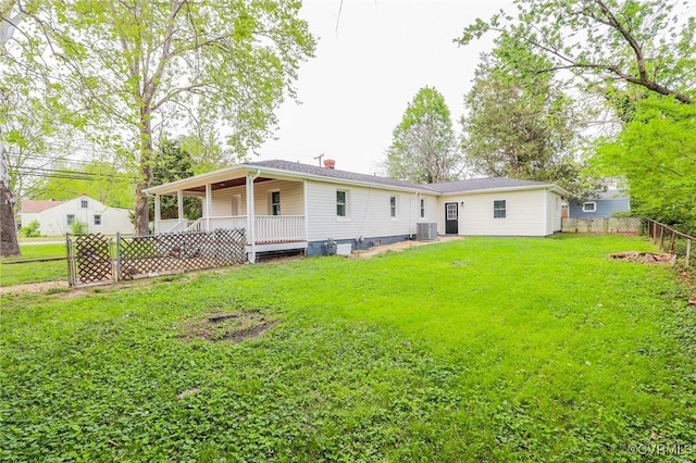 rear view of property featuring a lawn, central AC, a fenced backyard, and a chimney
