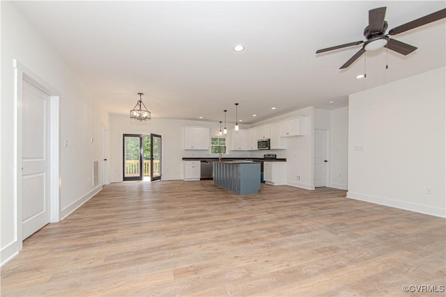 kitchen with a center island, open floor plan, appliances with stainless steel finishes, white cabinetry, and recessed lighting