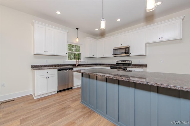 kitchen with visible vents, decorative light fixtures, light wood-style flooring, appliances with stainless steel finishes, and white cabinetry