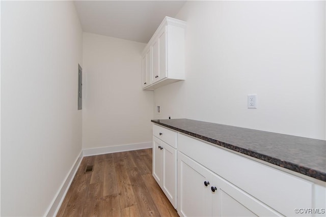 interior space with electric panel, baseboards, visible vents, and light wood-style floors