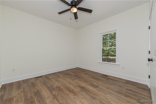 spare room featuring wood-type flooring, visible vents, baseboards, and ceiling fan