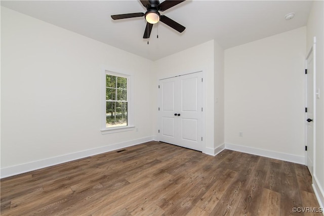 unfurnished bedroom featuring a closet, wood finished floors, visible vents, and baseboards