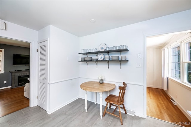 dining area featuring baseboards, visible vents, wood finished floors, and a fireplace