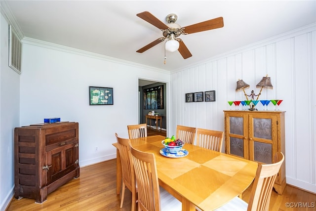 dining room featuring crown molding, a ceiling fan, baseboards, and light wood-style floors