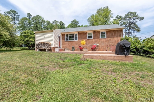 rear view of property with a lawn, brick siding, and a patio area