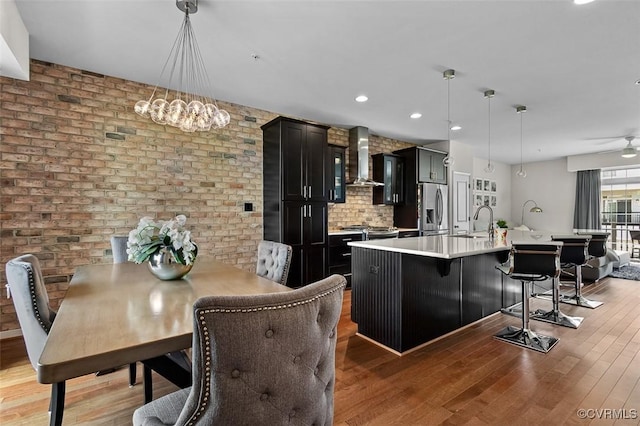 10925 Parkshire Ln, Henrico, VA 23233 - kitchen featuring stainless steel fridge, wall chimney range hood, dark cabinetry, light countertops, and a sink