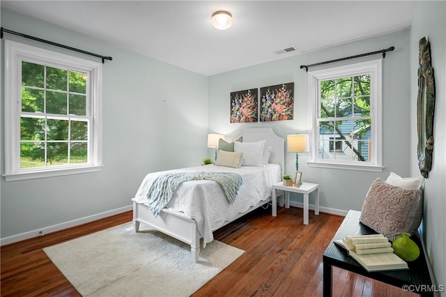 bedroom with multiple windows, wood finished floors, and visible vents