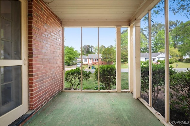 unfurnished sunroom featuring brick wall and wooden ceiling