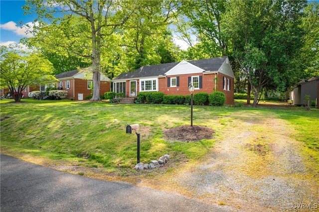 view of front of property with brick siding, driveway, and a front lawn