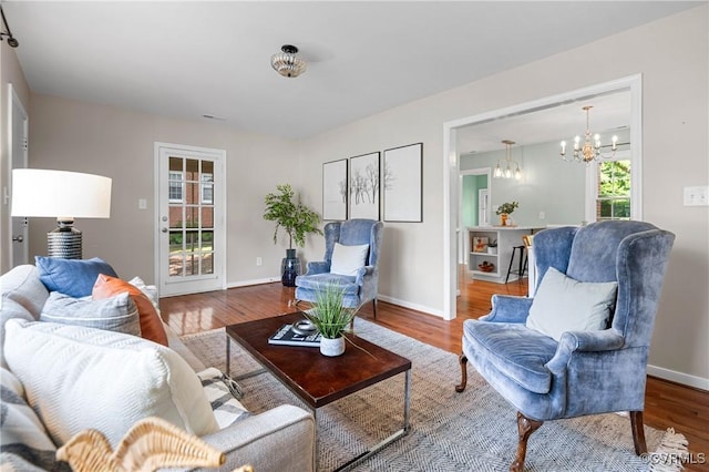 living area with an inviting chandelier, baseboards, and wood finished floors