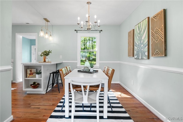 dining room with baseboards, wood finished floors, and a chandelier
