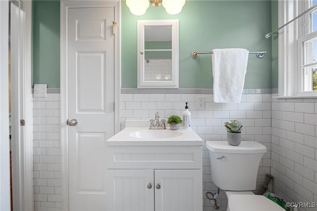bathroom with vanity, tile walls, wainscoting, and toilet