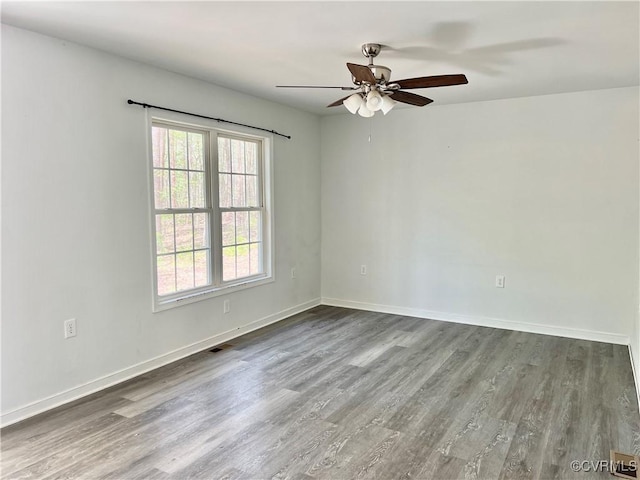 empty room featuring wood finished floors, visible vents, baseboards, and ceiling fan