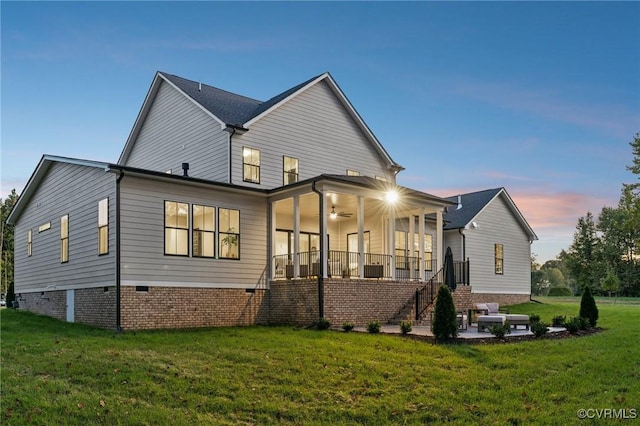 back of house at dusk featuring a lawn, stairway, ceiling fan, crawl space, and a patio
