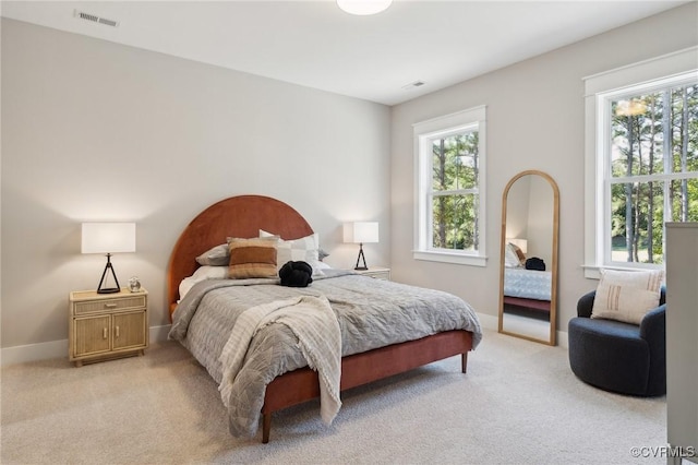 bedroom featuring baseboards, visible vents, light colored carpet, and multiple windows