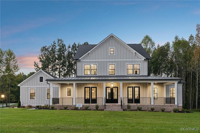 back of house at dusk with board and batten siding, french doors, a porch, and a standing seam roof