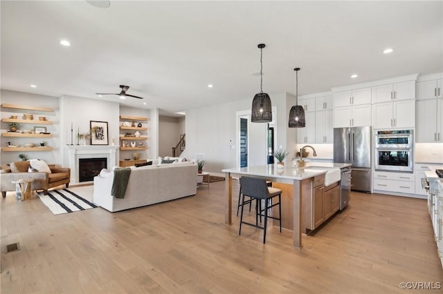 kitchen with a sink, open floor plan, a breakfast bar area, light wood-type flooring, and stainless steel appliances