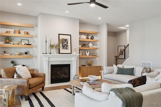 living room featuring a ceiling fan, a glass covered fireplace, light wood-style floors, visible vents, and recessed lighting