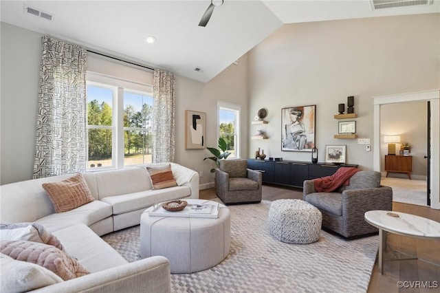 living area with wood finished floors, visible vents, high vaulted ceiling, and a ceiling fan