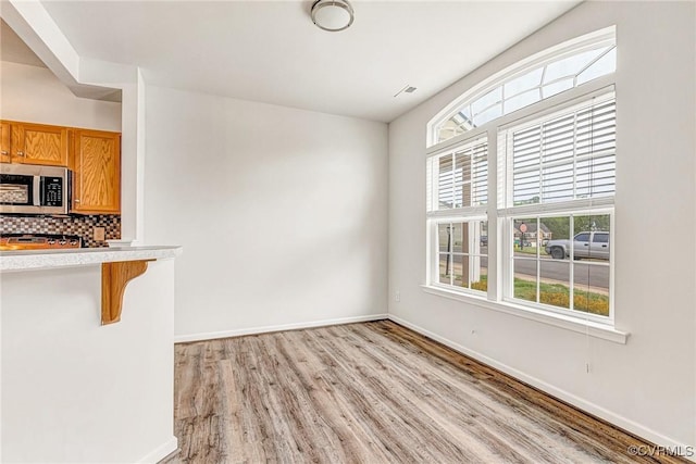 unfurnished dining area with plenty of natural light, baseboards, and light wood-type flooring
