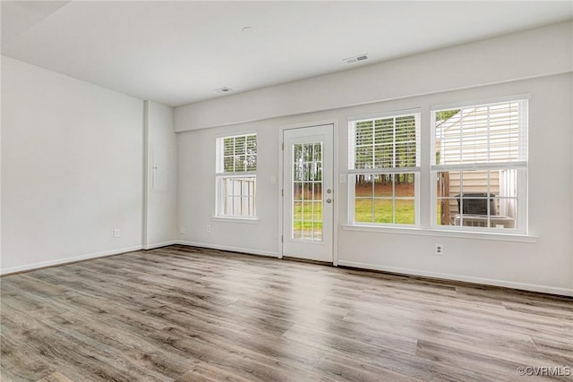 empty room with baseboards, wood finished floors, and visible vents