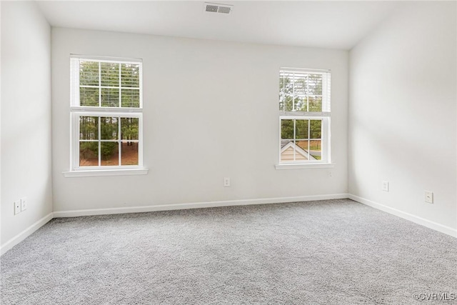 unfurnished room with baseboards, carpet floors, visible vents, and a wealth of natural light