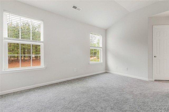 carpeted empty room with vaulted ceiling, visible vents, and baseboards
