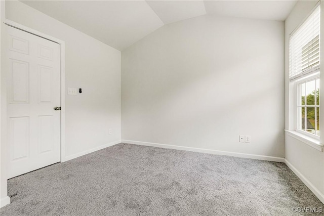 spare room with vaulted ceiling, carpet flooring, and baseboards