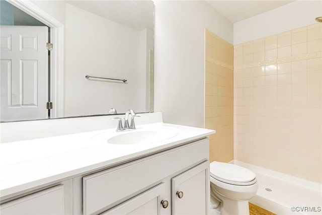 full bathroom with toilet, vanity, and tiled shower