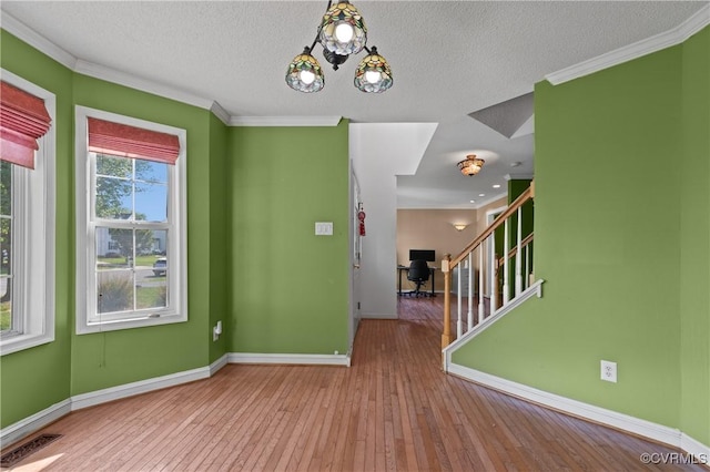 interior space with wood-type flooring, crown molding, visible vents, baseboards, and stairway