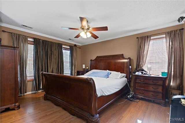 bedroom with visible vents, crown molding, and wood finished floors