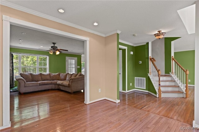living room featuring wood-type flooring, a ceiling fan, baseboards, visible vents, and stairway