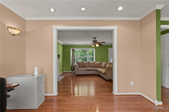living area with baseboards, ornamental molding, and light wood finished floors