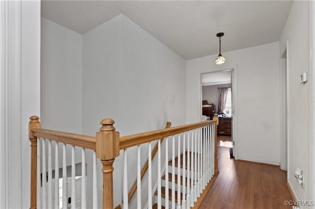 hallway featuring baseboards, hardwood / wood-style floors, and an upstairs landing