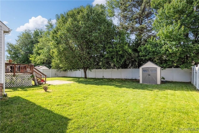 view of yard with stairs, a deck, a shed, a fenced backyard, and an outbuilding