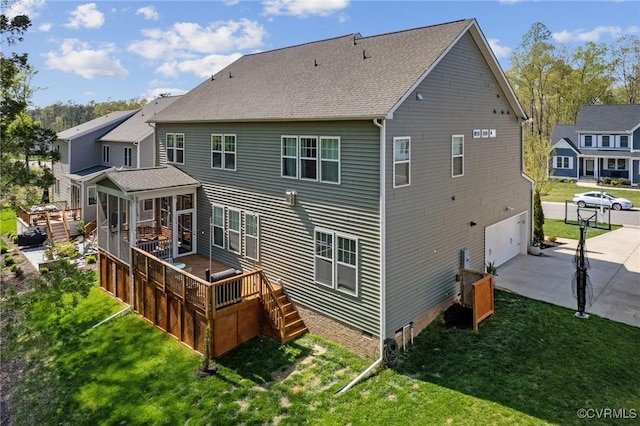 rear view of house featuring concrete driveway, a yard, an attached garage, and a deck