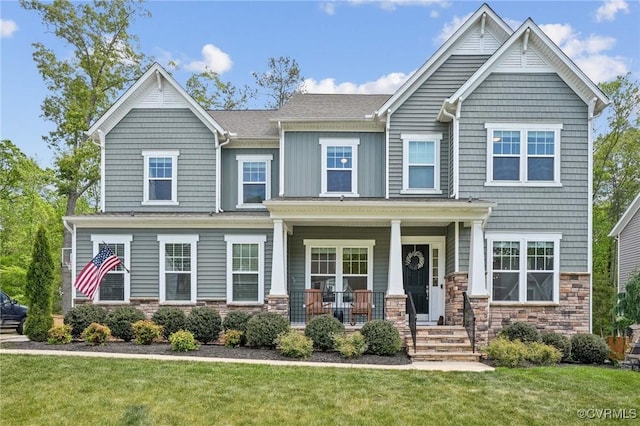 craftsman-style home with stone siding, a porch, and a front yard