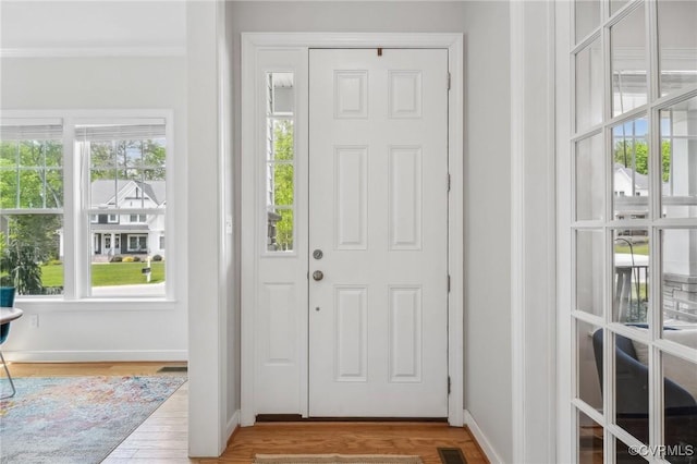 doorway to outside with baseboards, ornamental molding, and wood finished floors