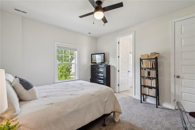 carpeted bedroom featuring a ceiling fan, ensuite bath, baseboards, and visible vents