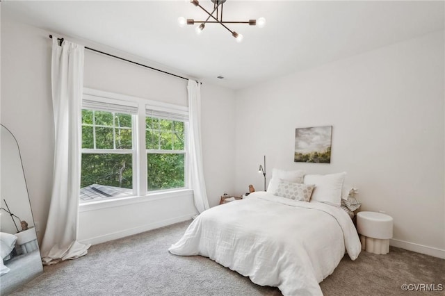 carpeted bedroom featuring baseboards and an inviting chandelier