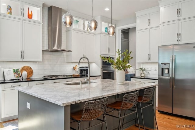 kitchen featuring stainless steel appliances, a center island with sink, backsplash, wall chimney range hood, and recessed lighting