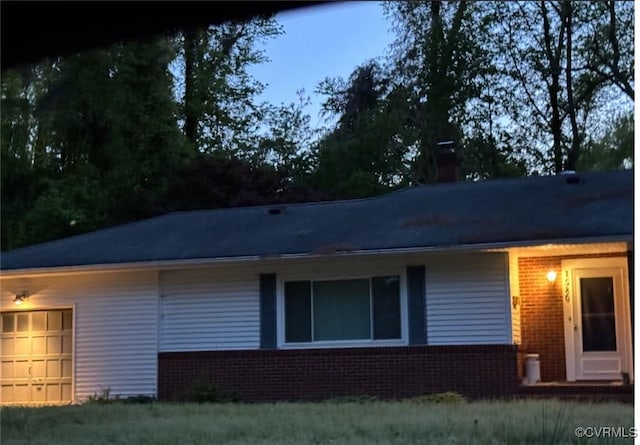 view of side of property with a garage, brick siding, and a chimney